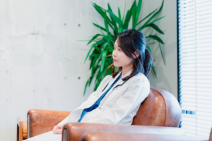 疲れを感じている看護師の女性が窓の外を眺めている様子